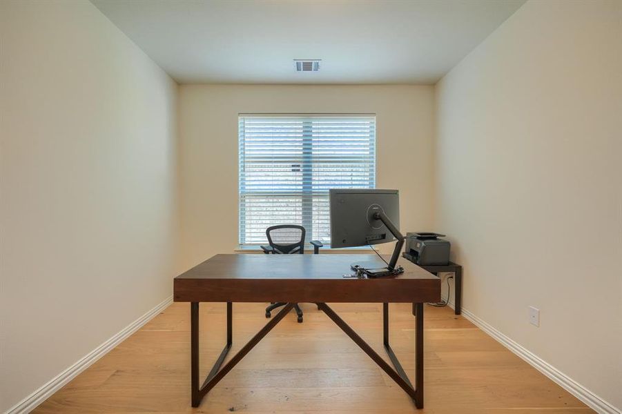 Office space with light hardwood / wood-style floors