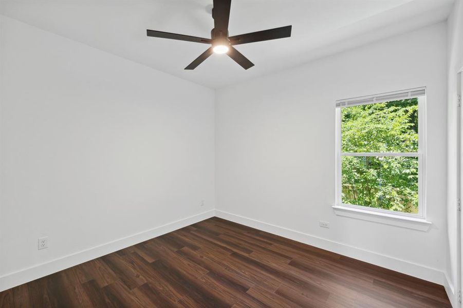 Empty room featuring a healthy amount of sunlight, dark hardwood / wood-style floors, and ceiling fan