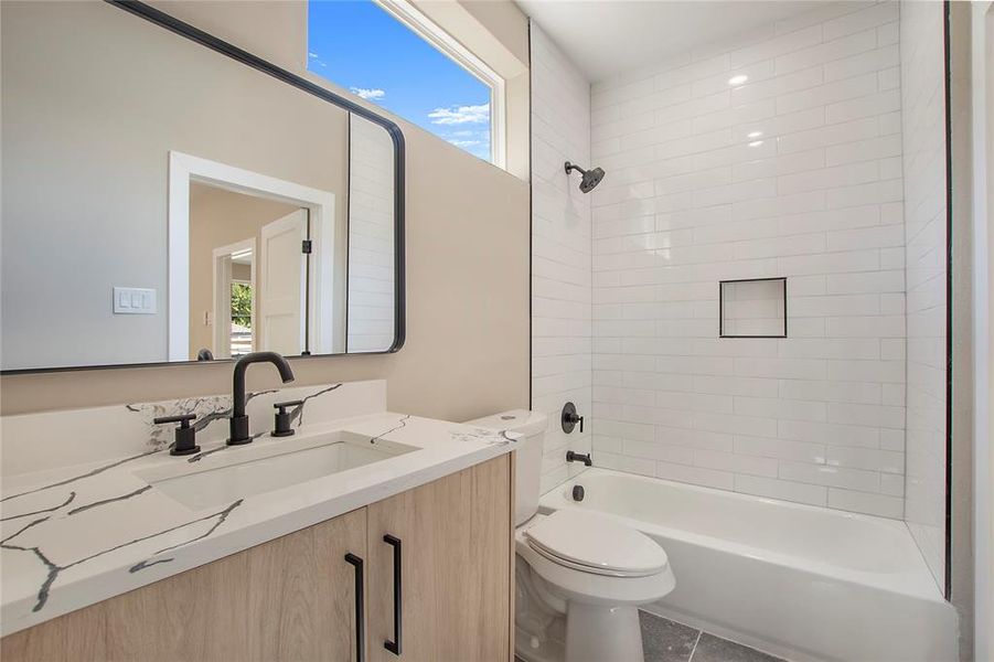 Full bathroom with tiled shower / bath combo, vanity, toilet, and tile patterned floors