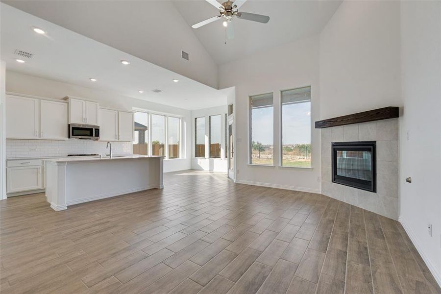 Kitchen with a fireplace, a kitchen island with sink, a wealth of natural light, and ceiling fan