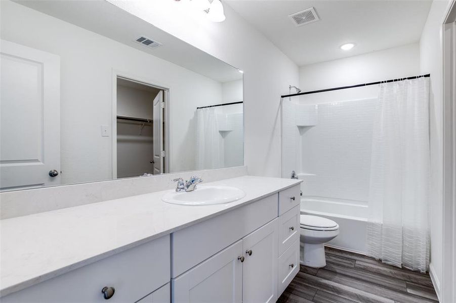 Full bathroom featuring shower / bathtub combination with curtain, vanity, toilet, and hardwood / wood-style floors