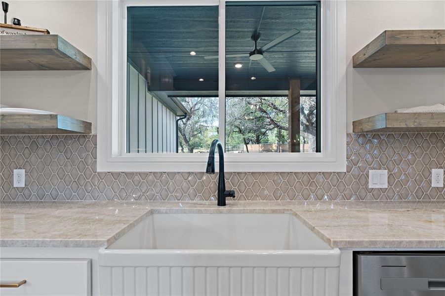 Kitchen with decorative backsplash, sink, white cabinets, and light stone counters