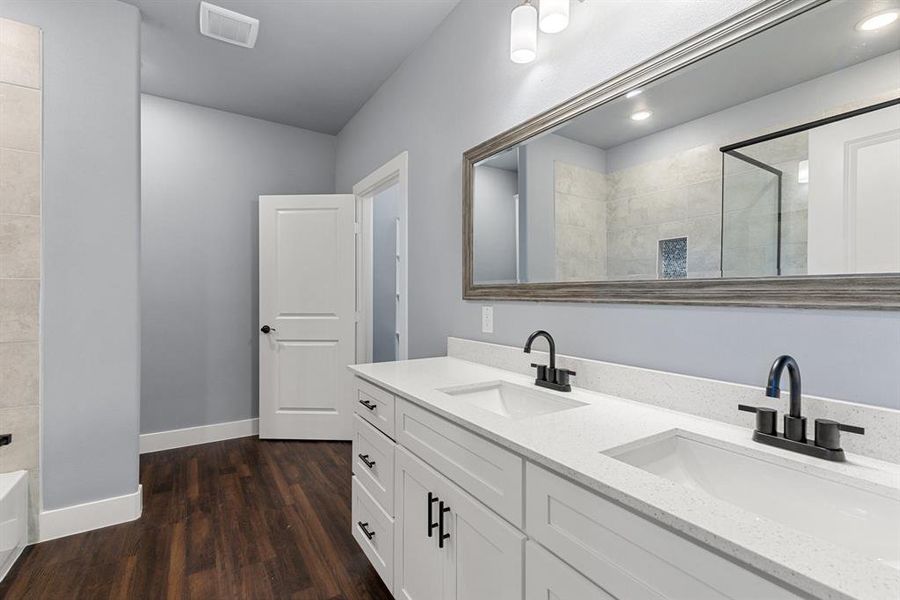 Bathroom with vanity, a tile shower, and wood-type flooring