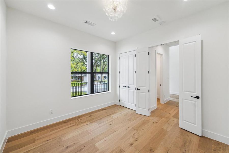 The first-floor study features engineered white oak flooring, designer neutral wall paint, and recessed LED lighting. Windows offer views of the front lawn and southern exposure, while a designer globe flush-mount light fixture adds a touch of elegance. The study also includes a convenient reach-in storage closet.