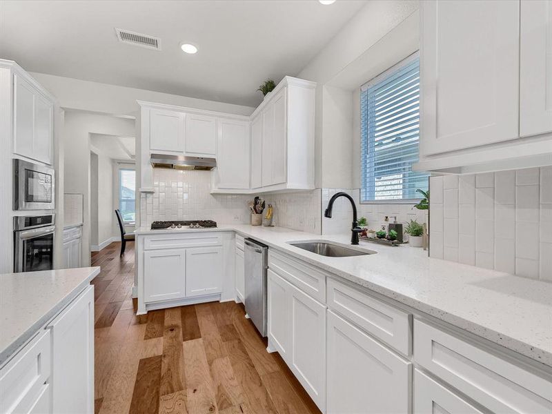 Kitchen with sink, white cabinetry, stainless steel appliances, and a healthy amount of sunlight