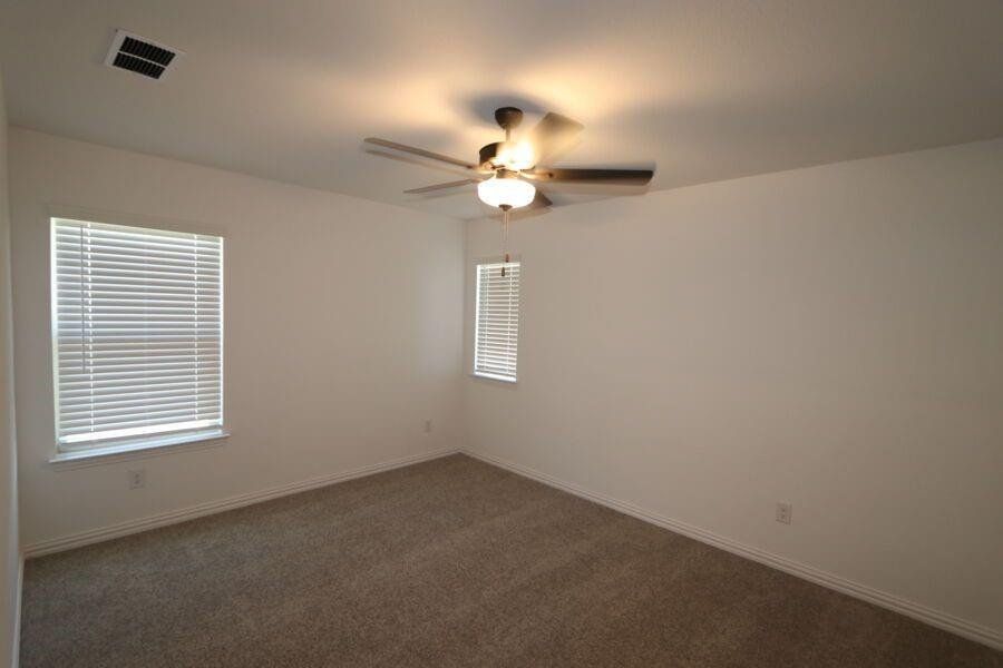 Unfurnished room featuring dark colored carpet and ceiling fan