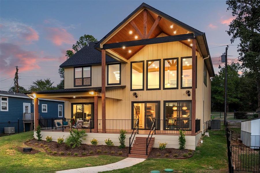 Back house at dusk with cooling unit, covered porch, and a yard