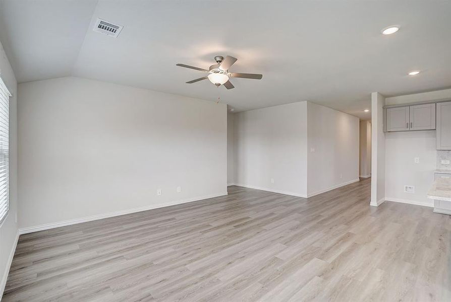 Living area with ceiling fan, vaulted ceiling, and light hardwood / wood-style floors