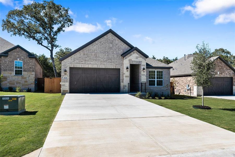 The Kendall plan at The Colony is a beautiful single-story home with a long driveway, gorgeous cedar garage door, and lush front yard landscaping.