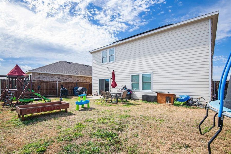 Rear view of house featuring a lawn, a patio, a trampoline, and a playground