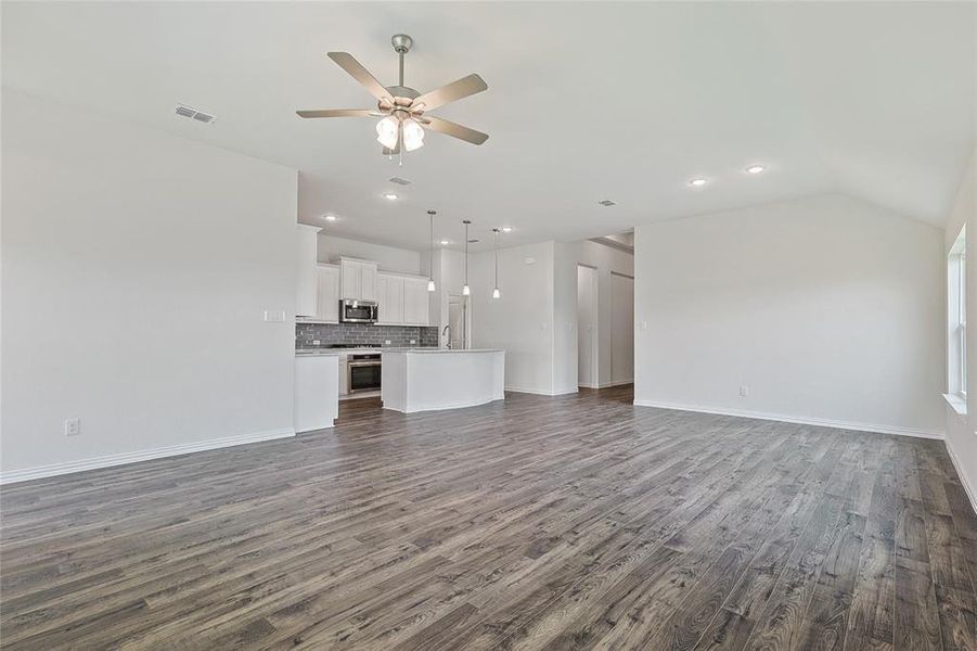 Unfurnished living room featuring lofted ceiling, dark hardwood / wood-style floors, and ceiling fan