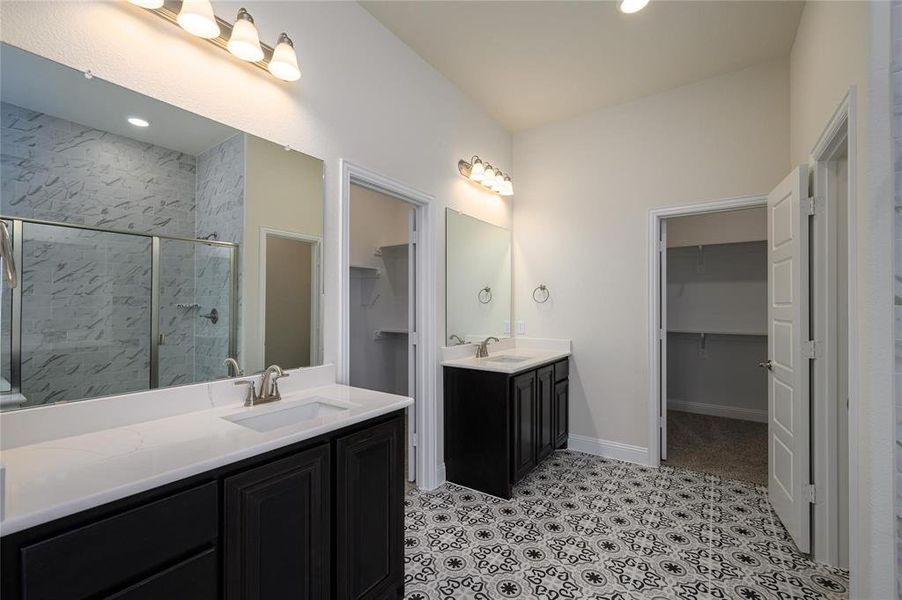 Bathroom with tile patterned flooring, walk in shower, and dual vanity