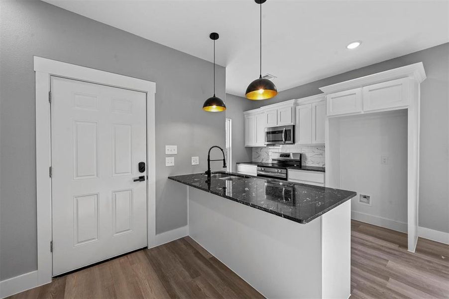 Kitchen with white cabinets, sink, decorative light fixtures, hardwood / wood-style flooring, and appliances with stainless steel finishes