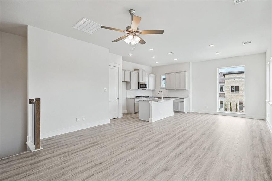 Unfurnished living room with sink, light wood-type flooring, and ceiling fan