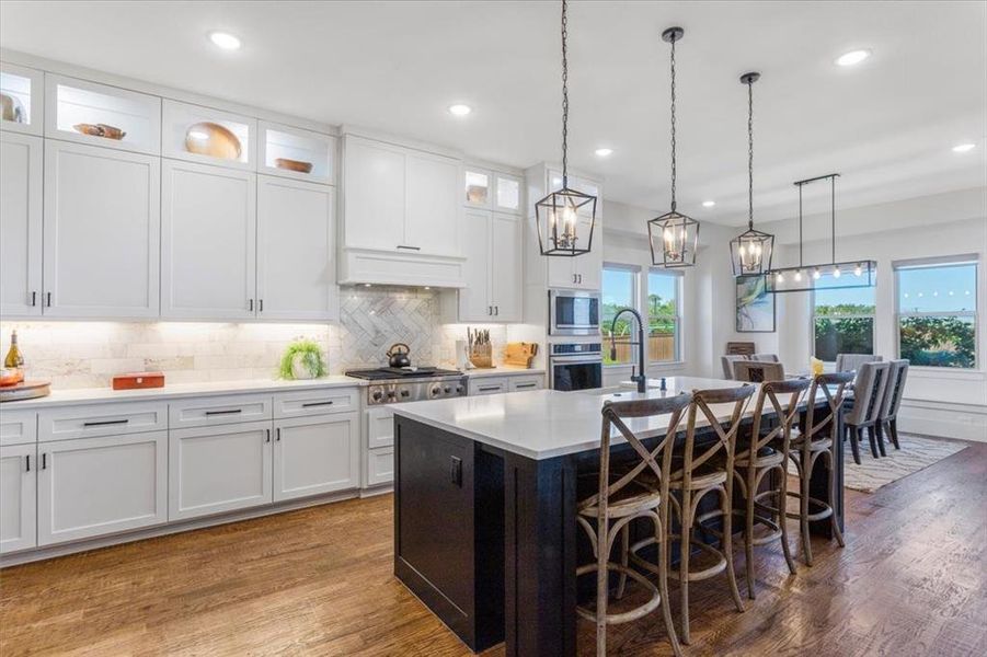 Kitchen with a wealth of natural light, white cabinetry, a center island with sink, and dark hardwood / wood-style floors