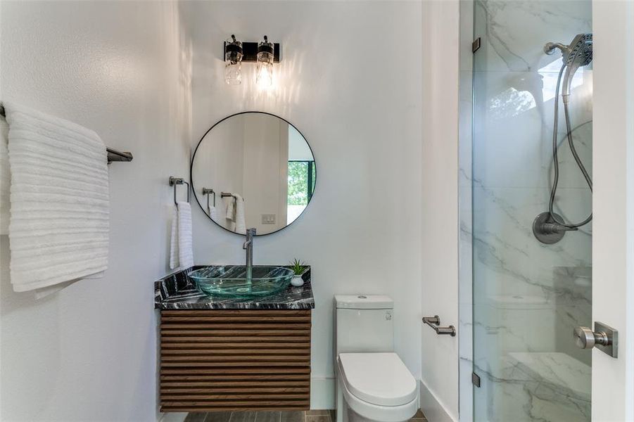 Bathroom featuring a shower with door, vanity, and toilet