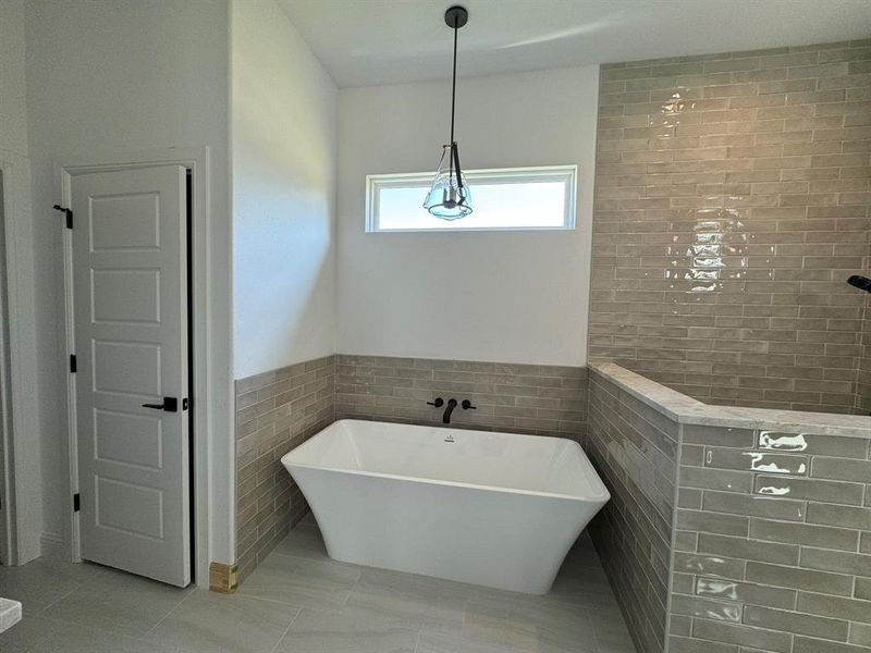 Bathroom featuring a bathtub, tile walls, and tile patterned floors