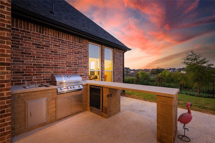 Patio terrace at dusk with sink, an outdoor kitchen, and a grill