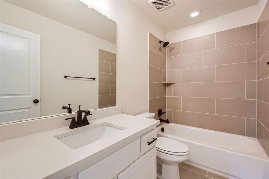 Full bathroom featuring tile patterned flooring, tiled shower / bath combo, vanity, and toilet