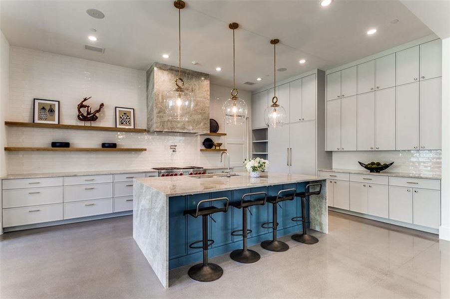 Kitchen with white cabinetry, backsplash, a kitchen island with sink