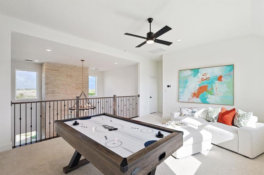 Game room with a wealth of natural light, brick wall, ceiling fan, and light colored carpet