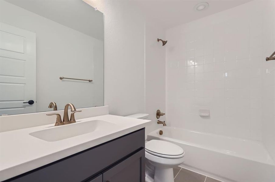 Full bathroom with vanity, tiled shower / bath, tile patterned flooring, and toilet