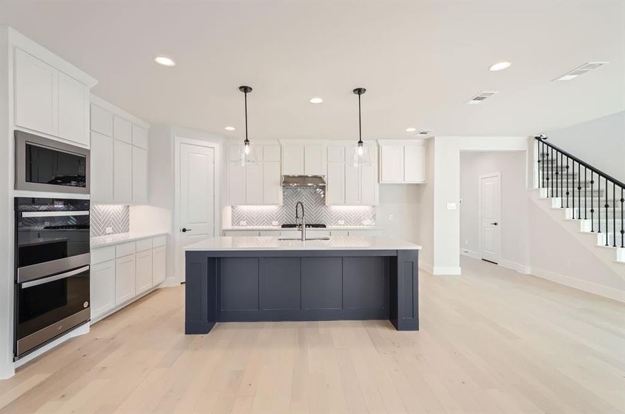 Kitchen with light wood-type flooring and white cabinets