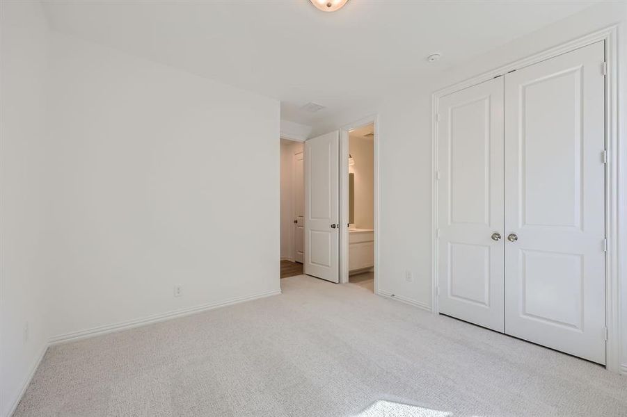 Unfurnished bedroom with light carpet, a closet, and connected bathroom