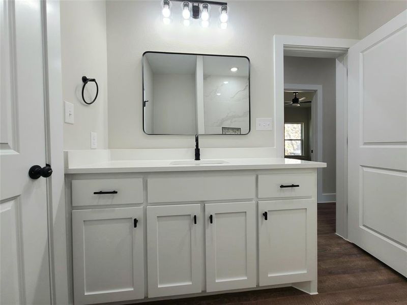 Bathroom with hardwood / wood-style floors, ceiling fan, and vanity