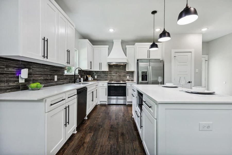 Kitchen featuring appliances with stainless steel finishes, sink, decorative backsplash, dark wood-type flooring, and custom range hood