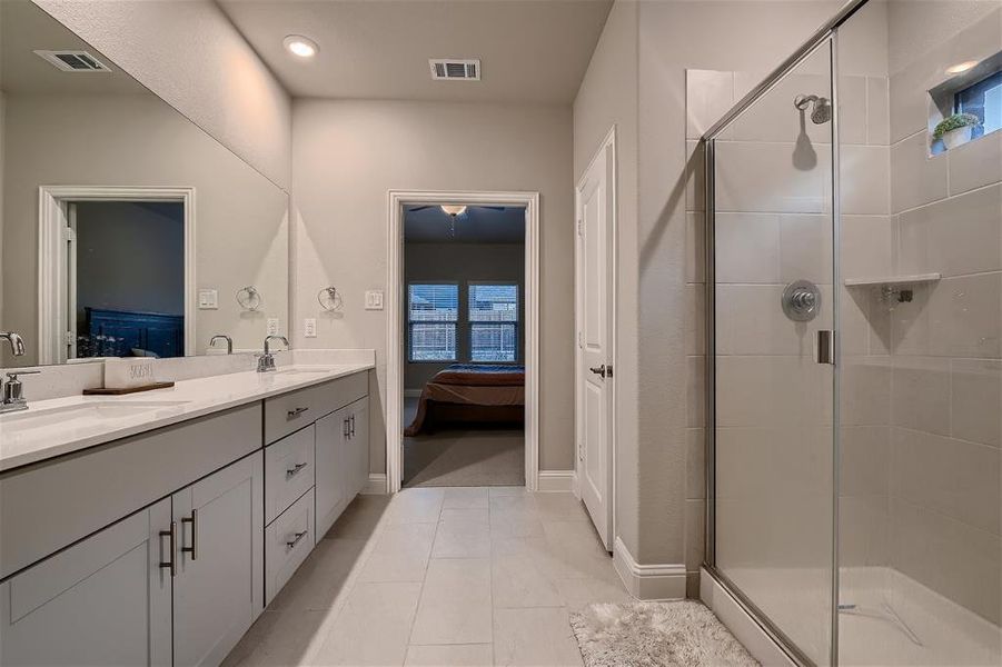 Bathroom featuring tile flooring, an enclosed shower, a healthy amount of sunlight, oversized vanity, and dual sinks