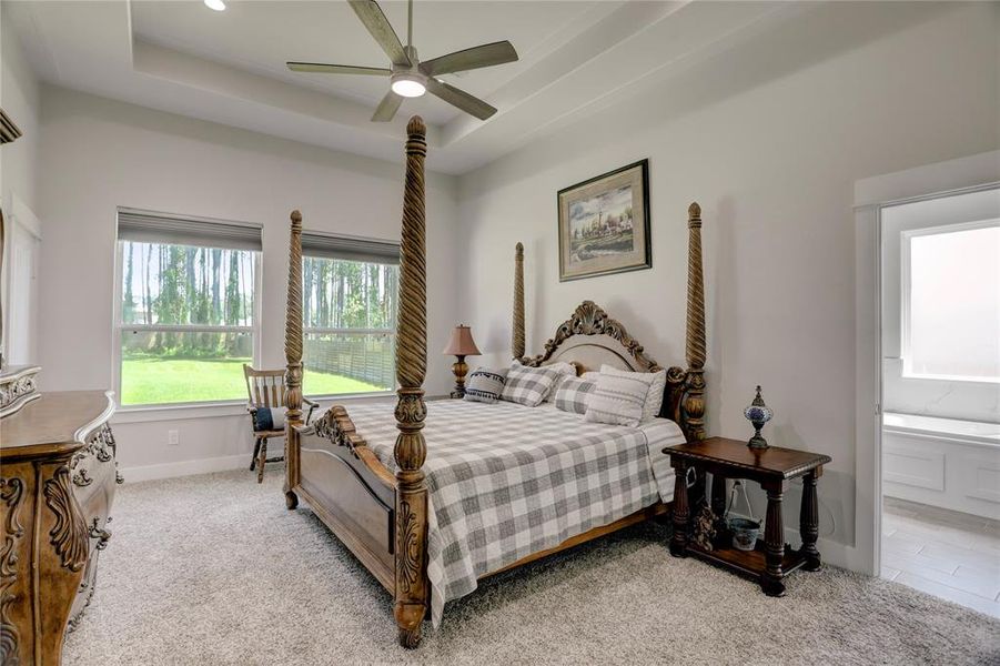 RETREAT TO THE MASTER BEDROOM WHERE GRANDEUR MEETS COMFORT, HIGHLIGHTED BY PLUSH CARPETING AND LARGE WINDOWS THAT FILL THE ROOM WITH NATURAL LIGHT.