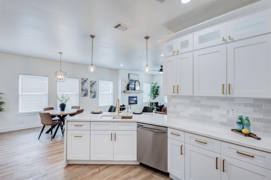 Kitchen featuring dishwasher, sink, light hardwood / wood-style floors, and backsplash