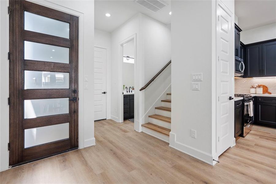 Step into a functional foyer upon entry, complete with a guest bath and tucked-away stairs leading to a secondary living area. The open layout seamlessly connects to the first-floor living area, creating a welcoming and versatile space for daily living and entertaining.