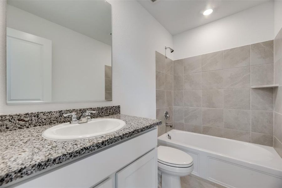 Full bathroom featuring tiled shower / bath combo, tile patterned floors, toilet, and vanity