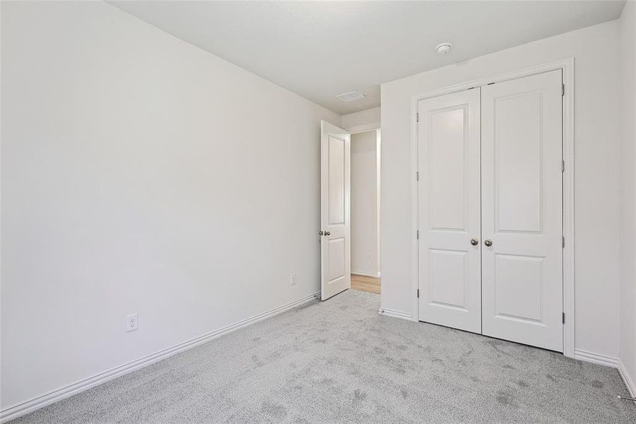 Unfurnished bedroom with light colored carpet and a closet