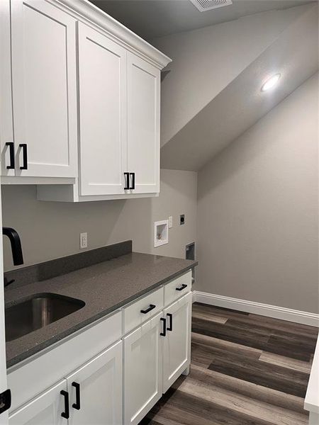 Kitchen featuring dark stone countertops, sink, dark hardwood / wood-style flooring, and white cabinetry