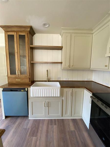 Kitchen with white cabinets, sink, range, dishwashing machine, and dark hardwood / wood-style flooring