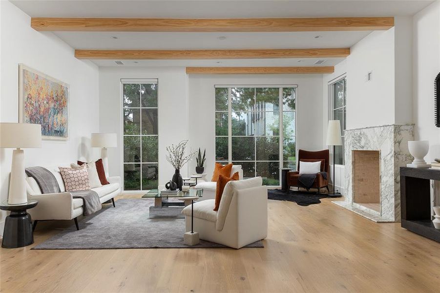 Living room featuring beam ceiling, a high end fireplace, and light wood-type flooring