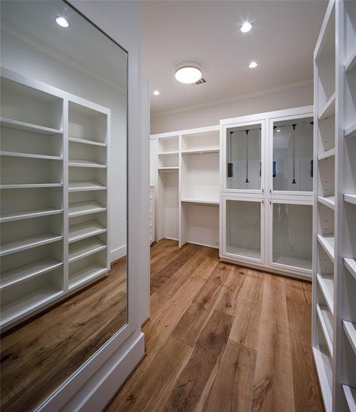 Gentlemen's dressing room with custom built-ins, pull down hanging rods, concealed safe and engineered French Oak floors