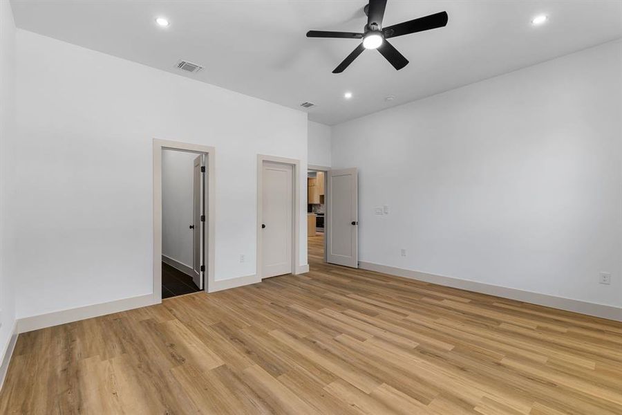 Unfurnished bedroom featuring a walk in closet, ceiling fan, and light wood-type flooring