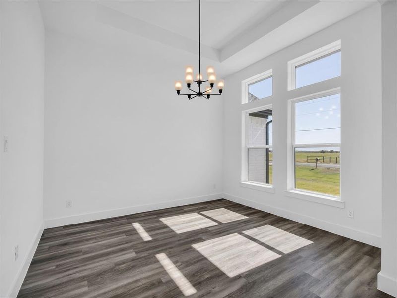 Unfurnished dining area with a chandelier, a high ceiling, and dark hardwood / wood-style flooring