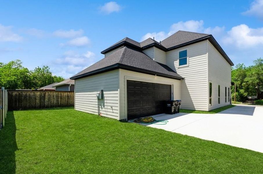 Back of house with a yard and a garage