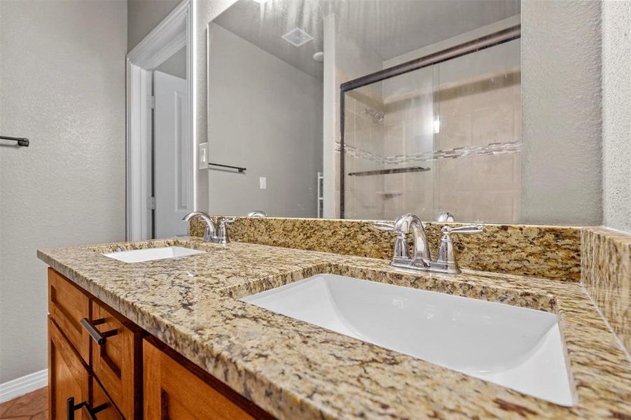 Primary Bathroom featuring a shower with door and double vanity