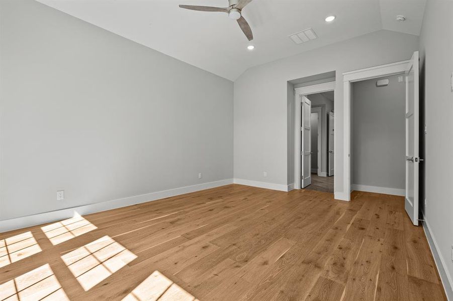 Unfurnished bedroom with vaulted ceiling, ceiling fan, and light hardwood / wood-style floors