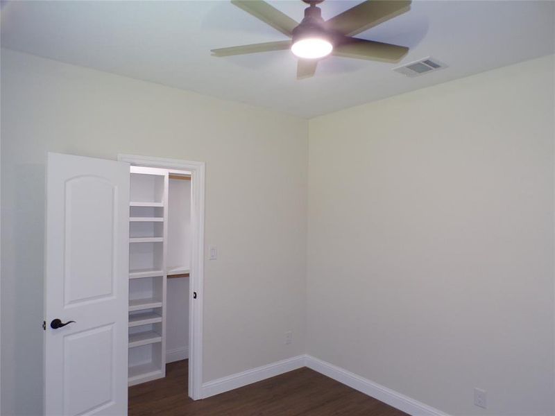 Unfurnished bedroom with dark hardwood / wood-style floors, a spacious closet, a closet, and ceiling fan