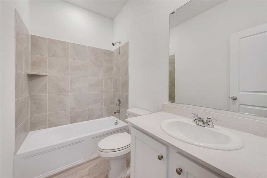 Full bathroom with toilet, tiled shower / bath, vanity, and wood-type flooring