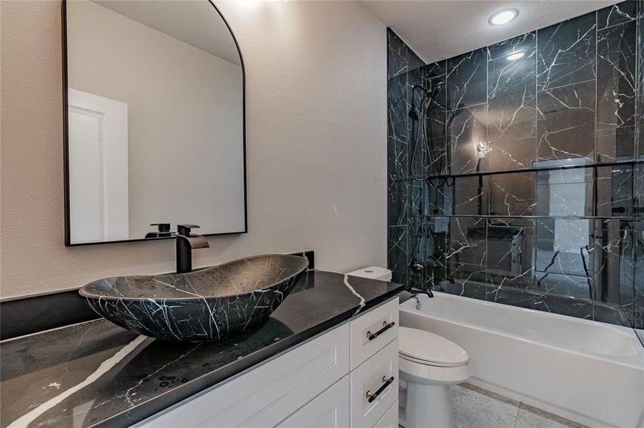 Full bathroom featuring vanity with extensive cabinet space, tile flooring, toilet, and tiled shower / bath combo