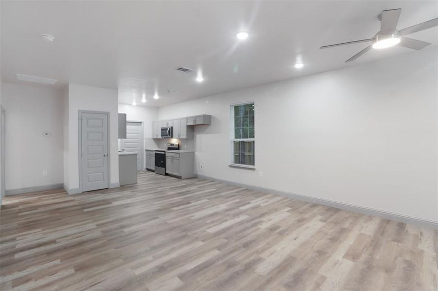 Unfurnished living room with ceiling fan and light hardwood / wood-style flooring