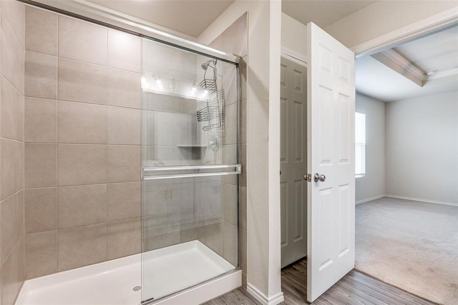 Bathroom featuring wood-type flooring, a raised ceiling, and walk in shower